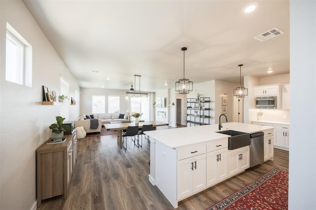 kitchen with dishwasher, a sink, dark wood finished floors, open floor plan, and white cabinets
