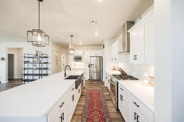 kitchen with stainless steel appliances, a sink, wall chimney exhaust hood, dark wood-type flooring, and recessed lighting