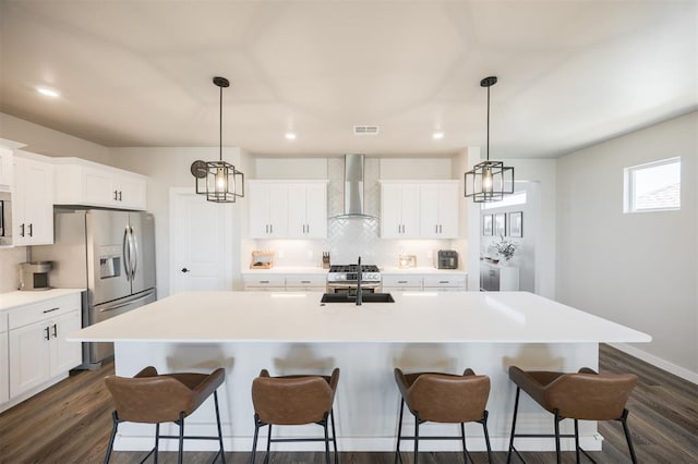 kitchen with wall chimney exhaust hood, stainless steel appliances, tasteful backsplash, a breakfast bar area, and a sink