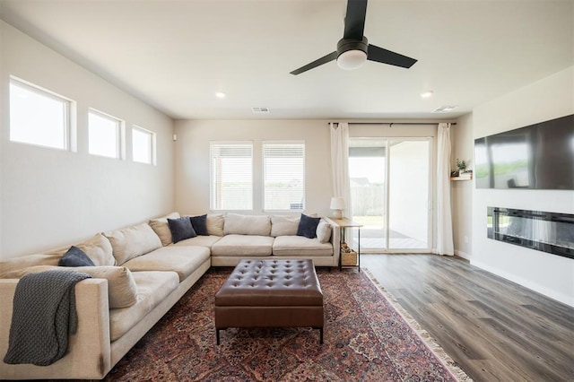 living room featuring wood finished floors, ceiling fan, recessed lighting, and a glass covered fireplace