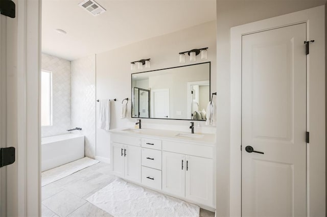 bathroom with double vanity, a garden tub, and a shower stall