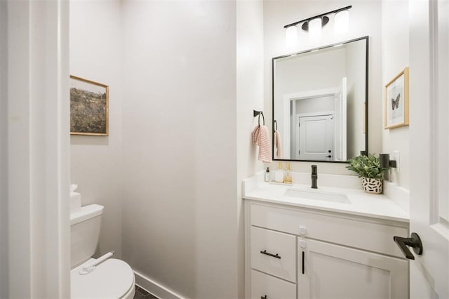 bathroom with toilet, vanity, and baseboards