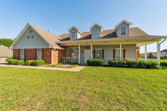 view of front of house featuring a front yard, brick siding, roof with shingles, and a porch