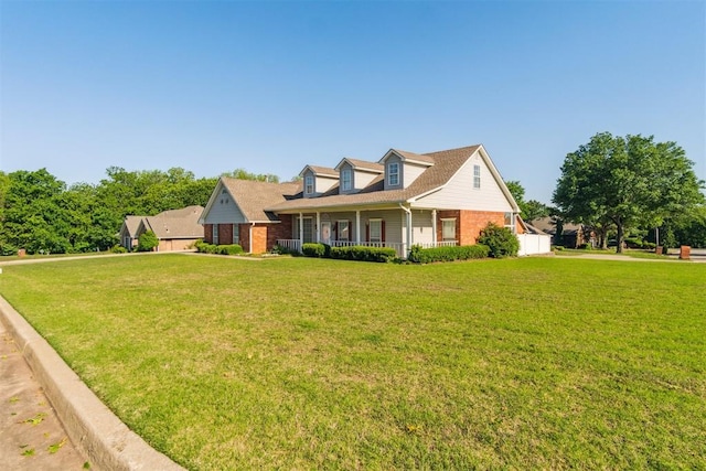 cape cod home with brick siding, a porch, and a front lawn