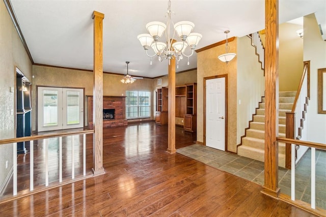 foyer entrance featuring wood-type flooring, a ceiling fan, stairs, crown molding, and a fireplace