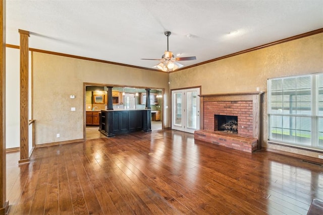 unfurnished living room with ornamental molding, ceiling fan, hardwood / wood-style flooring, a textured wall, and a fireplace