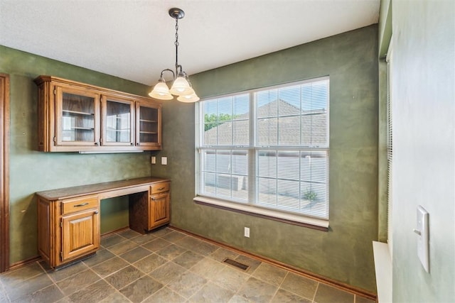 unfurnished office featuring built in desk, a chandelier, and baseboards