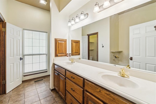 bathroom with toilet, double vanity, tile patterned flooring, and a tub to relax in