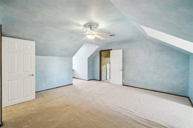 bonus room featuring lofted ceiling, carpet floors, ceiling fan, a skylight, and baseboards