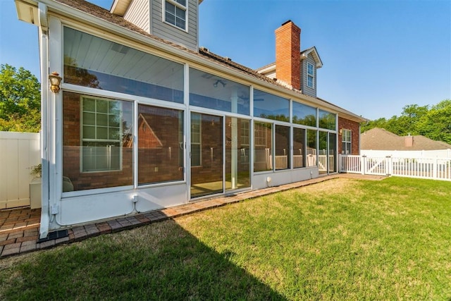 rear view of property with a sunroom, a chimney, and a gate