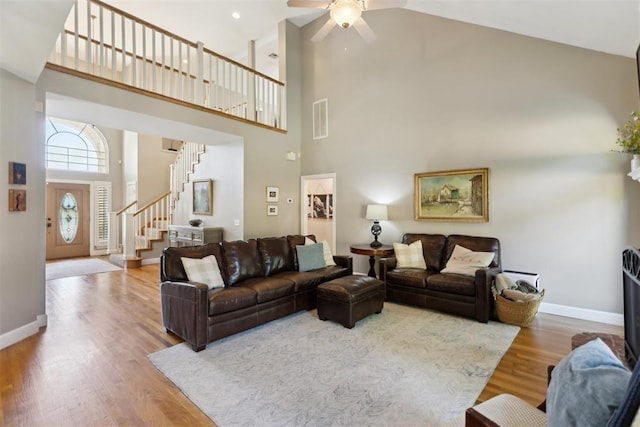 living room with high vaulted ceiling, stairway, ceiling fan, wood finished floors, and baseboards