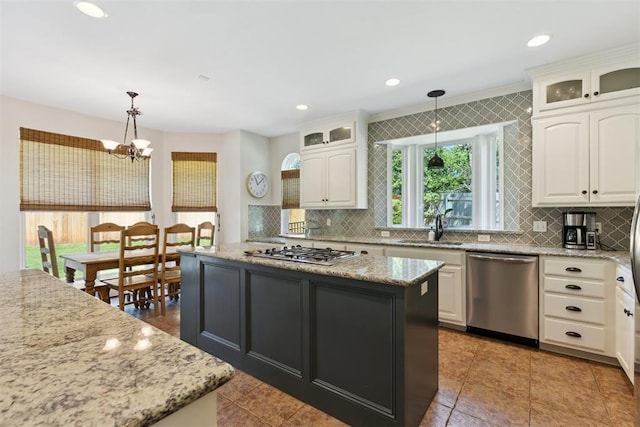 kitchen with appliances with stainless steel finishes, a kitchen island, a sink, white cabinets, and recessed lighting