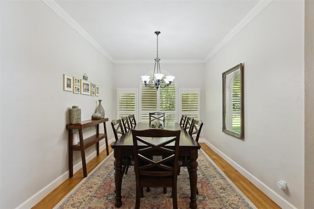 dining space with a chandelier, light wood-type flooring, crown molding, and baseboards