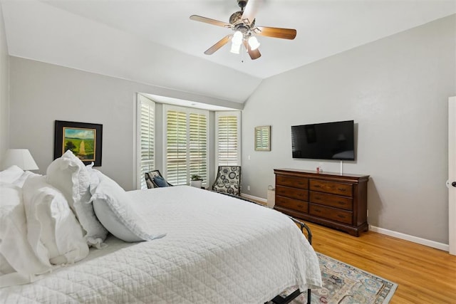bedroom featuring baseboards, light wood finished floors, lofted ceiling, and ceiling fan