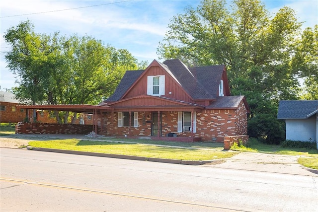 view of front of property featuring a shingled roof, a front yard, a porch, brick siding, and an attached carport