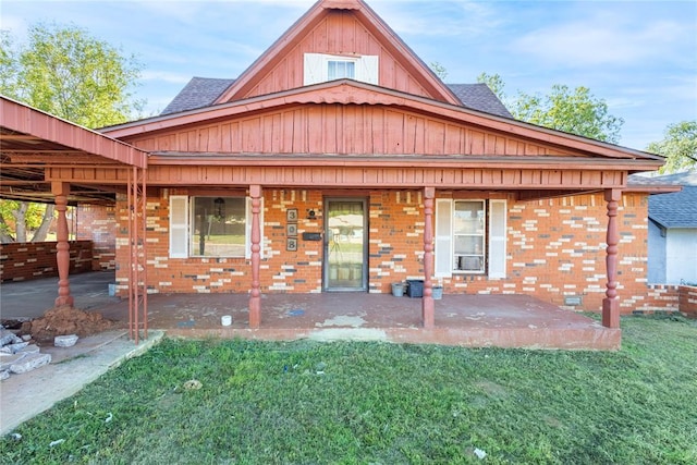 back of house with a yard, roof with shingles, brick siding, and board and batten siding