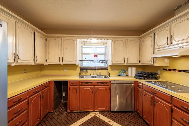 kitchen featuring appliances with stainless steel finishes, a sink, brick patterned flooring, and under cabinet range hood