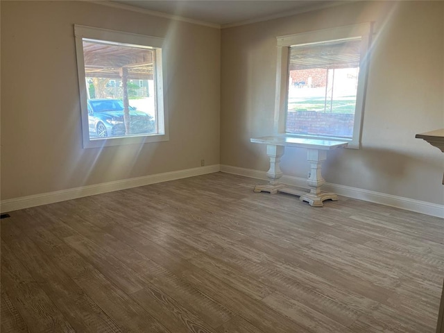 spare room with wood finished floors, ornamental molding, and baseboards