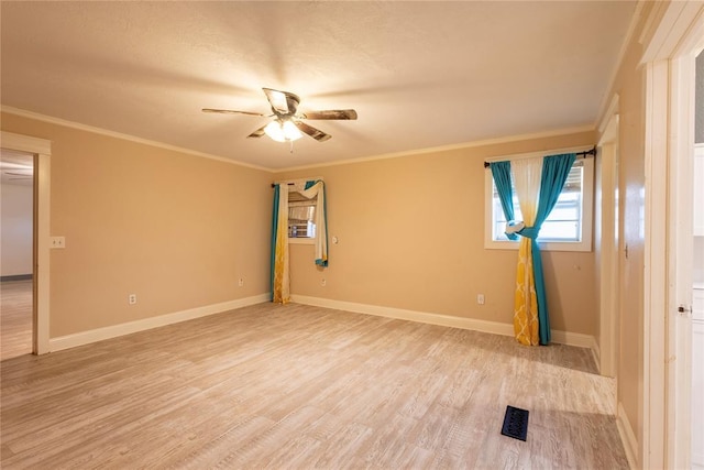 spare room featuring a ceiling fan, light wood-style floors, baseboards, and crown molding
