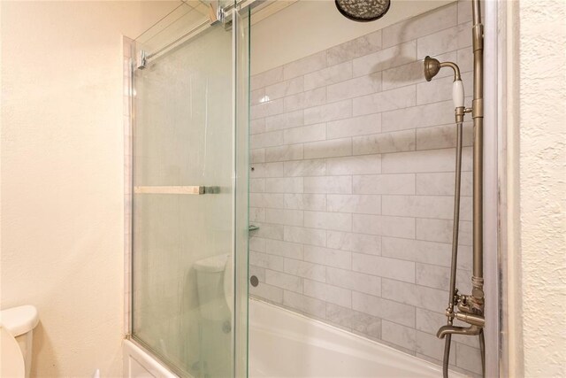 full bath featuring toilet and bath / shower combo with glass door