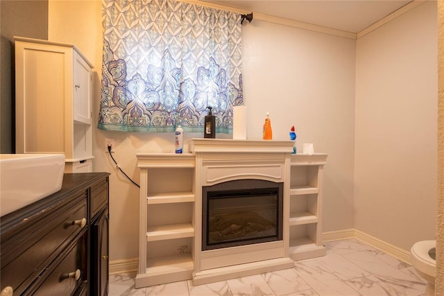 detailed view of baseboards, crown molding, a glass covered fireplace, and a sink