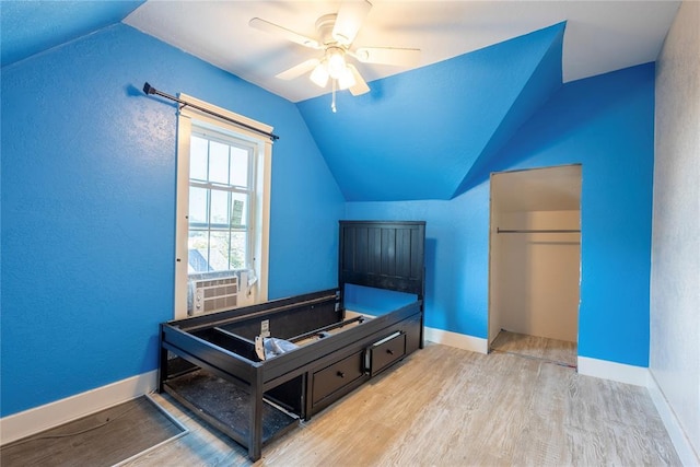 bedroom featuring wood finished floors, lofted ceiling, cooling unit, a closet, and baseboards