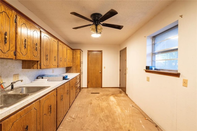 kitchen featuring a sink, brown cabinets, light countertops, and a ceiling fan