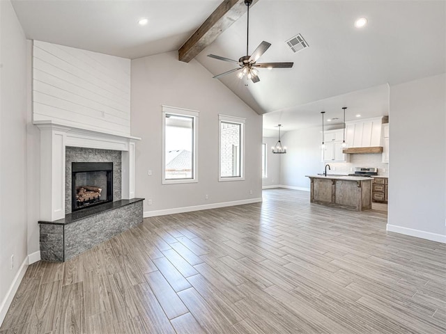 2716 Dunham Dr, Norman, OK 73071 - unfurnished living room with beamed ceiling, a ceiling fan, a premium fireplace, light wood finished floors, and baseboards