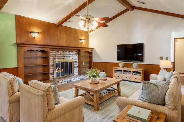 2613 SW 95th St, Oklahoma City, OK 73159 - living room featuring wood walls, a wainscoted wall, a ceiling fan, a fireplace, and wood finished floors