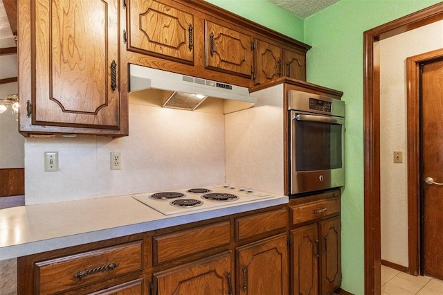2613 SW 95th St, Oklahoma City, OK 73159 - kitchen featuring under cabinet range hood, oven, white electric cooktop, and brown cabinets