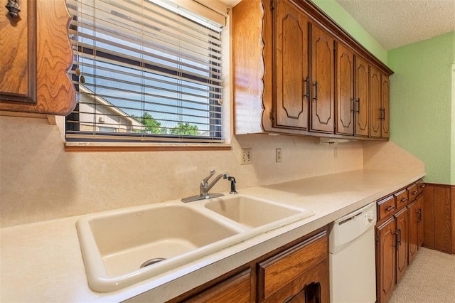 2613 SW 95th St, Oklahoma City, OK 73159 - kitchen featuring white dishwasher, a sink, brown cabinetry, wainscoting, and light countertops