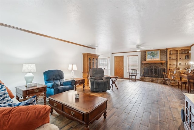living room featuring ceiling fan, wood finished floors, a brick fireplace, and ornamental molding