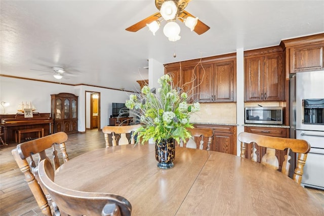 dining room featuring a ceiling fan, wood finished floors, and crown molding