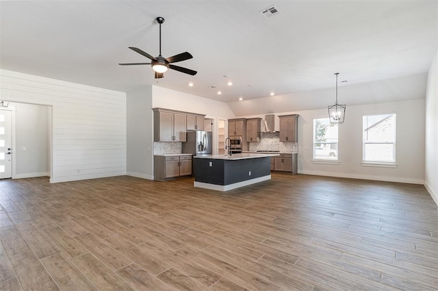 2246 Jackson Ln, Blanchard, OK 73010 - kitchen featuring open floor plan, vaulted ceiling, wall chimney range hood, decorative backsplash, and light countertops