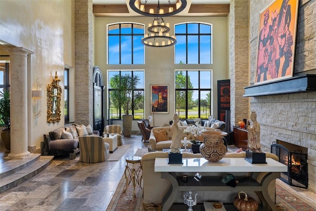 4400 NW 150th St, Oklahoma City, OK 73134 - living area featuring a fireplace, stone tile flooring, a towering ceiling, ornate columns, and a chandelier