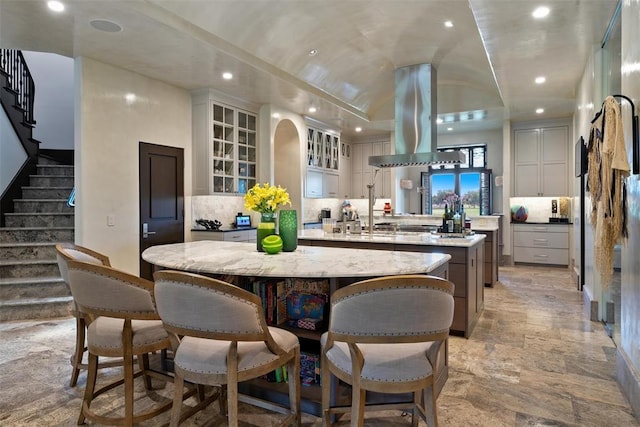 4400 NW 150th St, Oklahoma City, OK 73134 - kitchen featuring a center island with sink, island range hood, recessed lighting, tasteful backsplash, and glass insert cabinets