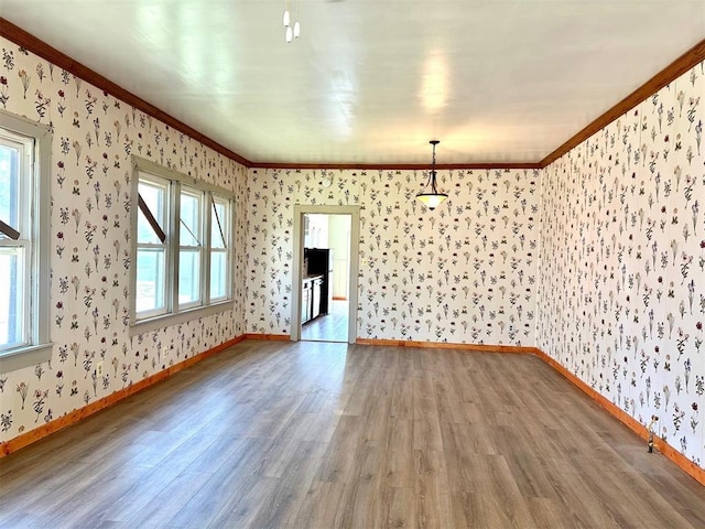 unfurnished room with wood finished floors, wallpapered walls, baseboards, and ornamental molding