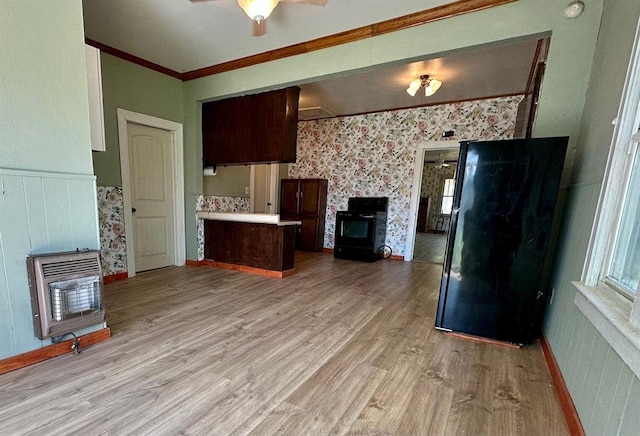 kitchen with crown molding, light wood finished floors, light countertops, open floor plan, and a wood stove