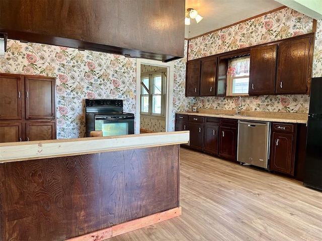 kitchen featuring wallpapered walls, black appliances, light countertops, plenty of natural light, and light wood-style floors