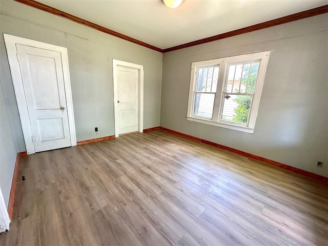 empty room with ornamental molding, wood finished floors, and baseboards