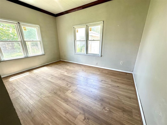 empty room featuring wood finished floors, ornamental molding, and baseboards