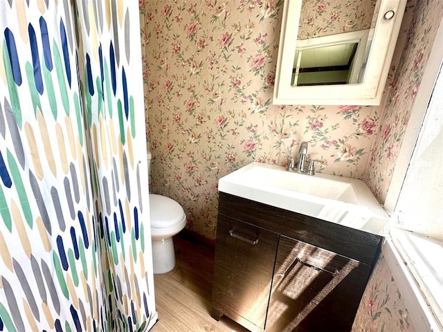 full bath featuring wallpapered walls, wood finished floors, vanity, and toilet