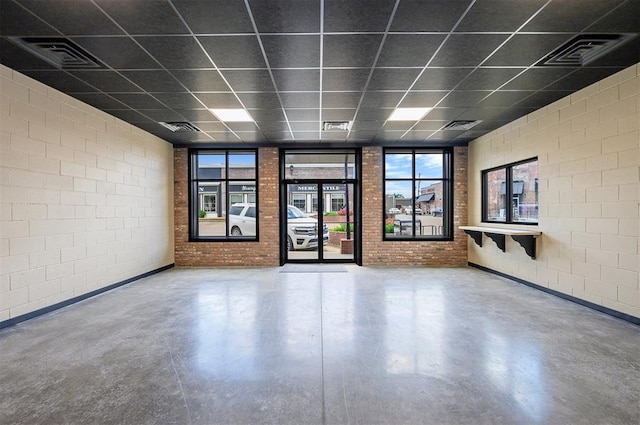 124 N Main St, Broken Bow, OK 74728 - unfurnished room featuring finished concrete flooring, a drop ceiling, brick wall, and concrete block wall