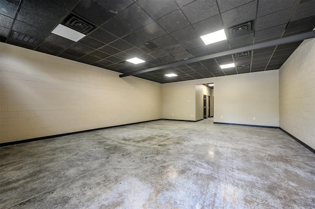 124 N Main St, Broken Bow, OK 74728 - empty room featuring concrete flooring, baseboards, a drop ceiling, and concrete block wall