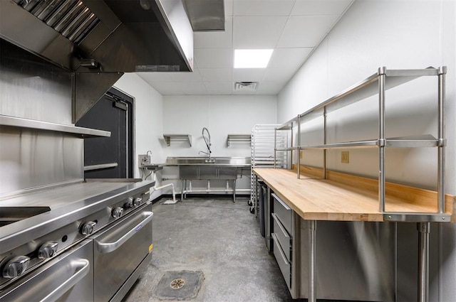 124 N Main St, Broken Bow, OK 74728 - kitchen with wood counters, concrete floors, a paneled ceiling, ventilation hood, and range with two ovens