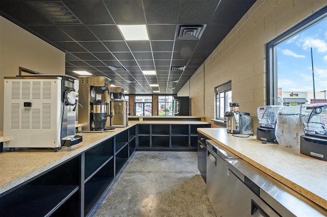124 N Main St, Broken Bow, OK 74728 - kitchen featuring open shelves, concrete block wall, light countertops, a drop ceiling, and concrete floors