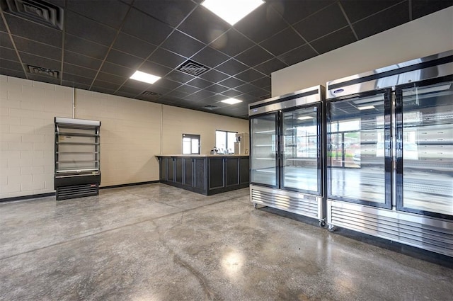 124 N Main St, Broken Bow, OK 74728 - unfurnished room featuring finished concrete floors, concrete block wall, and a drop ceiling