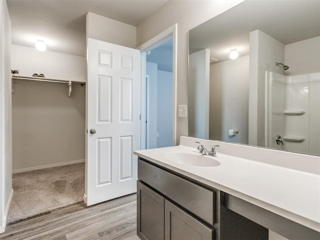 full bath with wood finished floors, vanity, a shower, and baseboards
