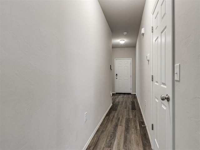 corridor featuring dark wood-style flooring and baseboards