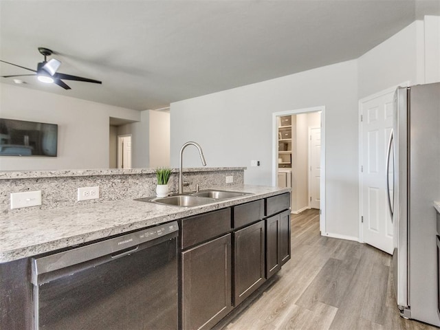 kitchen featuring dishwasher, a sink, freestanding refrigerator, light wood-type flooring, and dark brown cabinets